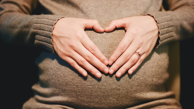 A parent's hands cradling a pregnant belly
